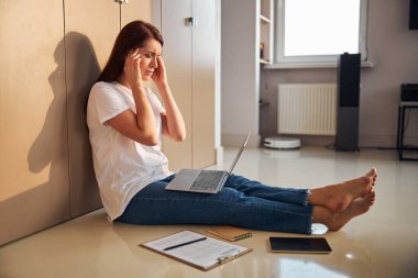 Uzun saçlı genç bir kadın şakaklarına dokunuyor.