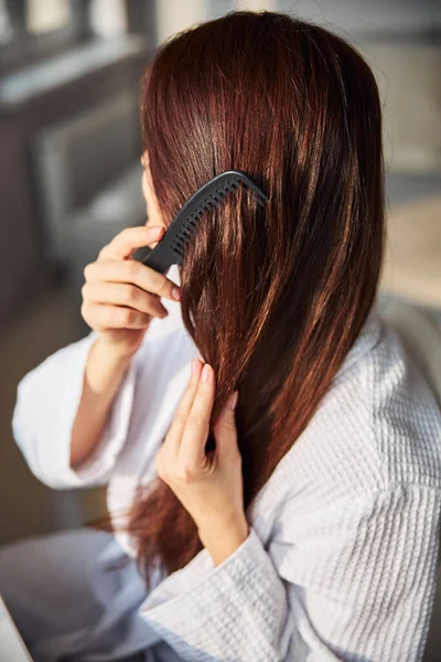 Κοντινό πλάνο νεαρής γυναίκας που χτενίζει τα μαλλιά της — Φωτογραφία Αρχείου