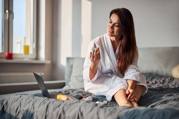 Positiv förtjust brunett kvinna sitter på sängen — Stockfoto