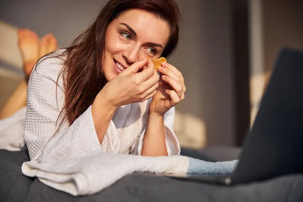 Glada brunett kvinna tittar skönhet tutorials online — Stockfoto