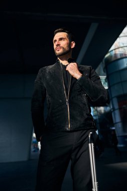 Yakışıklı genç gezgin tek başına dikilirken yakasına dokunuyor.