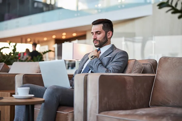 Serious businessman using his laptop in the hall and frowning — Stock Photo, Image