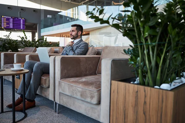 Yakışıklı iş adamı havaalanı koridorunda ciddi görünüyor.