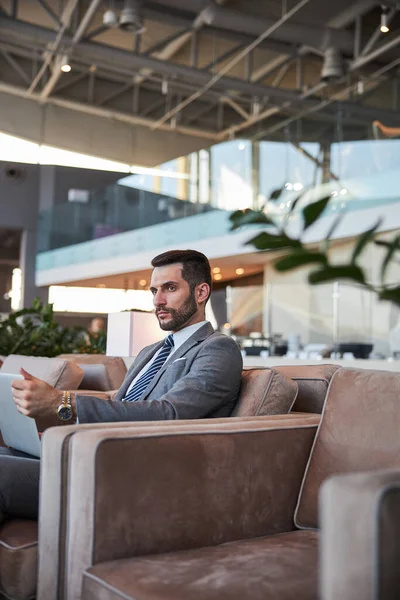 Modern aletlerle düşünceli bir iş adamı tek başına oturuyor.