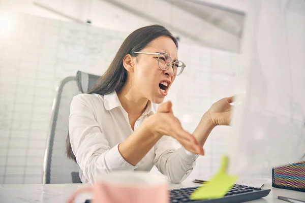 Емоційна брюнетка жінка кричить на її комп'ютер — стокове фото