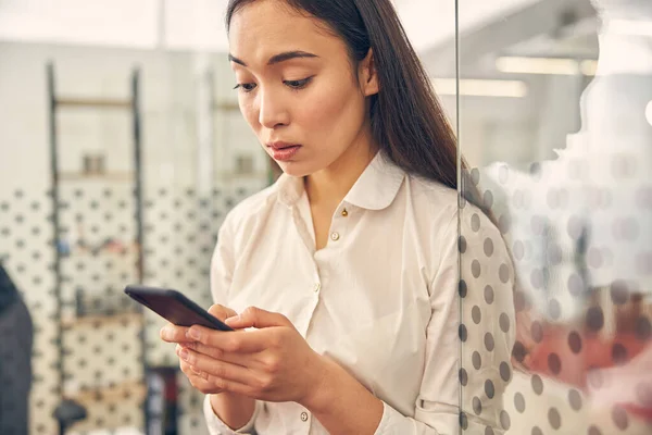 Emocional mujer internacional mirando fijamente su teléfono inteligente —  Fotos de Stock