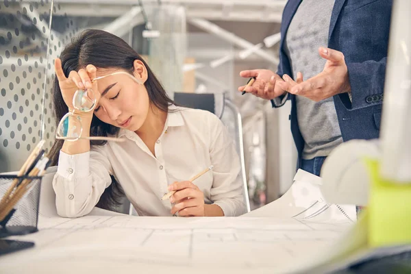 Müde brünette weibliche Person sitzt an ihrem Arbeitsplatz — Stockfoto