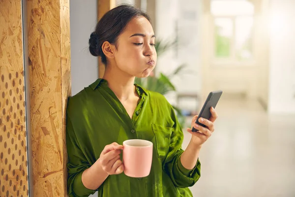 Emotional brunette female staring at her telephone — Stock Photo, Image
