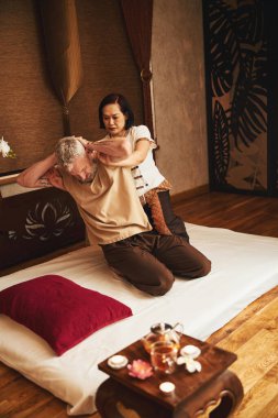 Yaşlı hastayı jimnastikle tedavi eden Asyalı kadın.