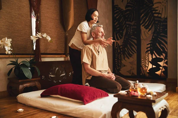 Mulher asiática fazendo massagem tradicional para homem grisalho — Fotografia de Stock