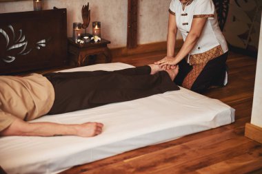 Asyalı kadın erkek için geleneksel masaj yapıyor.