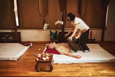 Asyalı kadın olgun erkek için rehabilitasyon egzersizleri yapıyor.