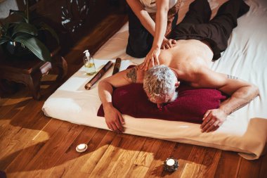 Tayland spa merkezinde boz saçlı bir adam masaj yaptırıyor.