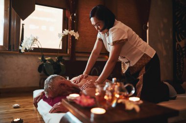 Asyalı kadın erkek için geleneksel masaj yapıyor.