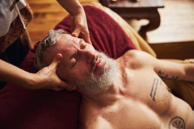 Sakince ağarmış adam kafa masajı sırasında dinleniyor.