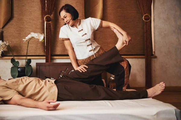 Mulher asiática alegre tratando pés masculinos no estúdio de massagem — Fotografia de Stock