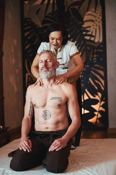 Radosna Azjatka robi masaż dla mężczyzny w pracy — Zdjęcie stockowe