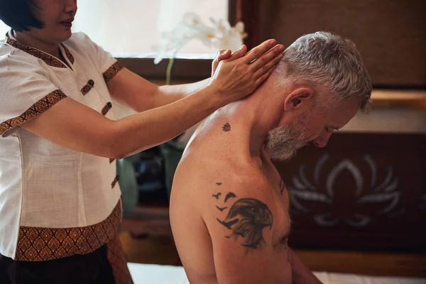 Tatuaż Dojrzały mężczyzna podczas tajskiej terapii w studio — Zdjęcie stockowe