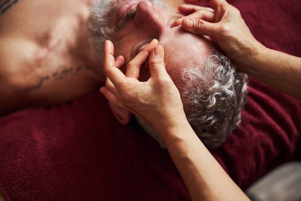 Grizzled man tijdens handmatige gezichtsbehandeling in spa — Stockfoto