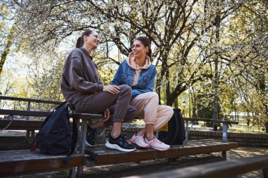 Ceketli bir kadın gülümseyen bir kadına bakıyor.