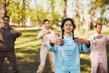 Huzurlu Asyalı Qigong eğitmeni önünde el ele tutuşuyor.