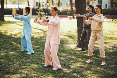 Qigong uygulayıcıları önlerindeki boşluğu kollarıyla sarıyorlar.