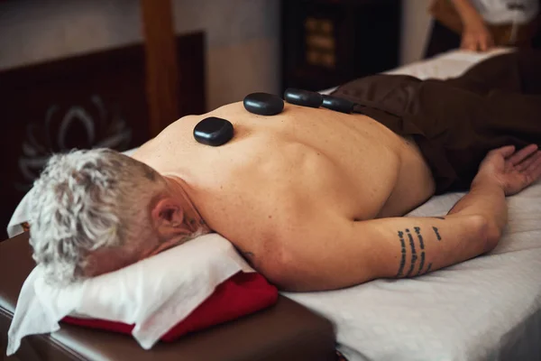 Hombre en topless relajante después del masaje con piedras —  Fotos de Stock