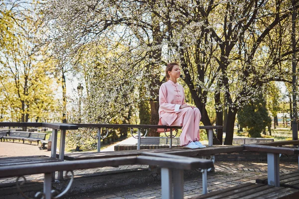 화창 한 공원 벤치에 앉아 핑크 색 옷을 입은 여성을 명상하는 모습 — 스톡 사진