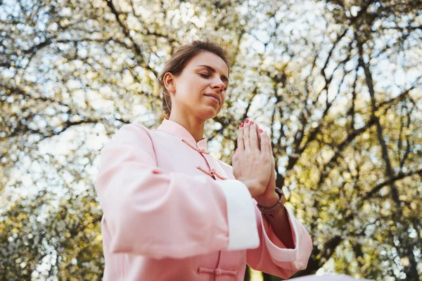 Mujer artista marcial haciendo gesto de manos rezando con los ojos cerrados —  Fotos de Stock