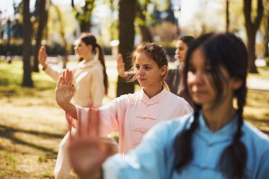 Dişiler Tai Chi sırasında avuçlarını açıp kollarını öne doğru itiyorlar.