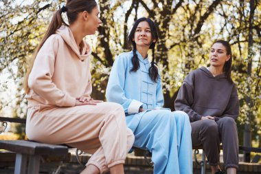 Tai Chi eğitmeni iki kadın arasında oturuyor.