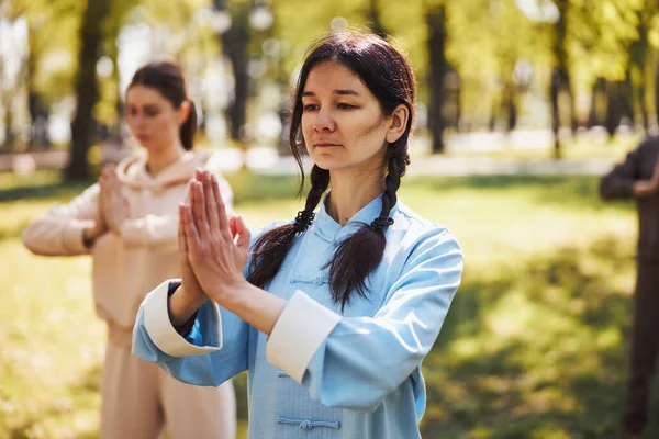 Профессиональный мастер ушу демонстрирует молитвенную позу на занятиях на открытом воздухе — стоковое фото