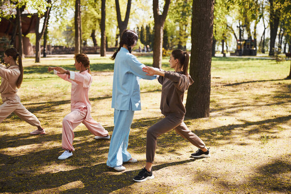 Тренер Тайцзицюань исправляет позу своей ученицы в коричневой одежде