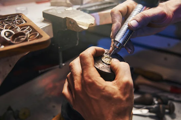 Jewelry expert bringing power drill to golden pendant — Stock Photo, Image