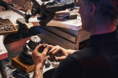 Kuyumcu parmağına yüzük takıyor.