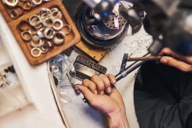 Mücevher imalatçısı, halkayı dikmek için çekiç kullanıyor.