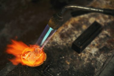 Metal eritme sırasında lehim lambası kullanan kişi