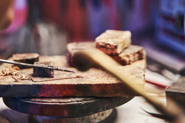 Golden chain lying on stone during soldering — Stock Photo, Image