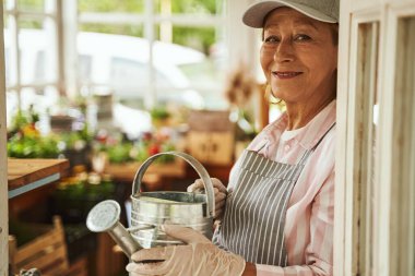 Sulama kutusuyla gülümseyen güzel yaşlı bayan.