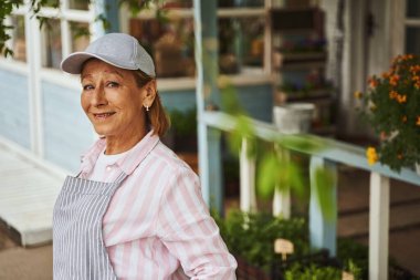 Kırsal verandanın yanında gülümseyen yaşlı bayan.