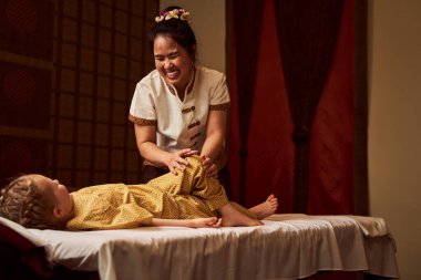 Çinli doktor gülümseyen ve mutlu bir çocuğa bakıyor.