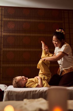 Çocuk terapistin yardımıyla fiziksel egzersiz yapıyor.