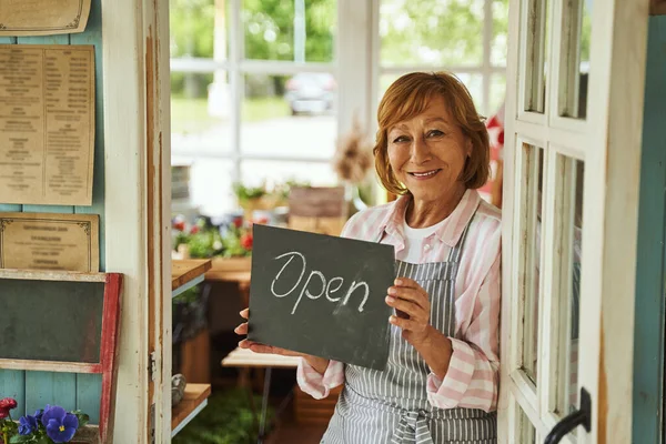 Happy woman welcoming customers to rural shop — Stock Photo, Image