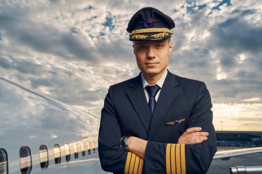 Kollarını kavuşturup ileriye bakan sakin erkek pilot.