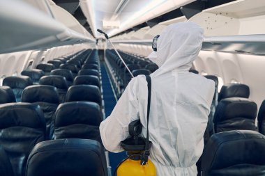 Deneyimli bir havayolu çalışanı yolcu kabinini dezenfekte ediyor.