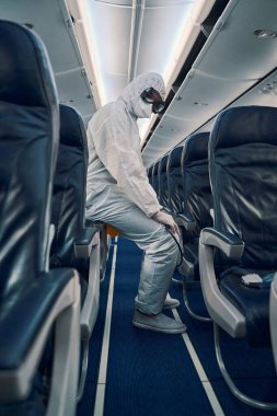 Antiviral kabin dezenfeksiyonundan sonra kameraya poz veren bir işçi.