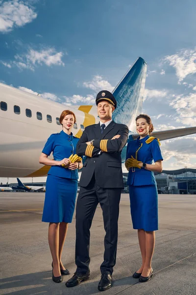 Pilot a dvě letušky stojící na letišti — Stock fotografie