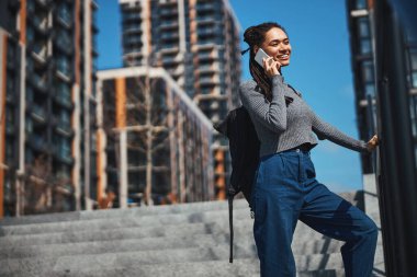 Gülümseyen mutlu kadın merdivenlerde telefonla konuşuyor.
