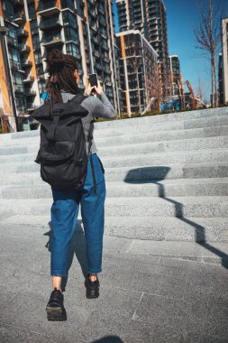 Saçları örgülü bir kadın yeni yerleşim yerinin dijital fotoğraflarını çekiyor.