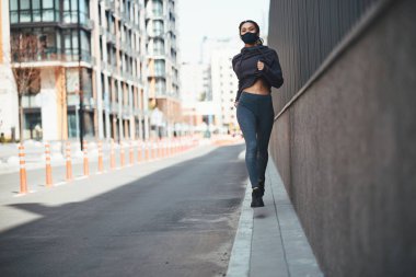 Şehir caddesinde koşan örgü örgülü mutlu bir koşucu.